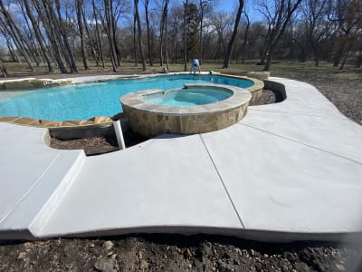 Custom freeform pool with tanning ledge and fire pit in a naturalistic retreat at the Isaac Residence in Anna, TX