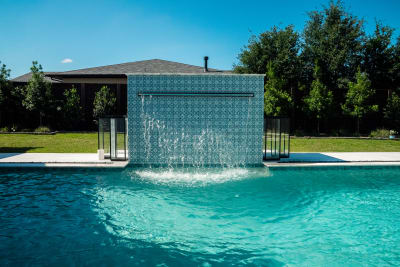 Aerial establishing view of a contemporary geometric infinity-edge pool with raised spa and 8-foot sheer descent on a Colleyville, TX estate.