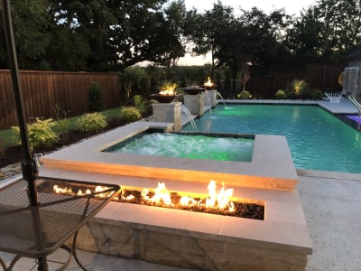 Raised spa with Arctic White Peerless Pebble interior and Leudar Buff coping cascading a 10-foot spillover into the main pool at a Tarrant County estate in Arlington, TX.