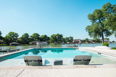 Close-up material detail of travertine patio coping and concrete pavers beside a geometric pool shell in Azle, Parker County, TX.
