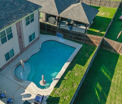 Material-detail view of Aquabella Caribbean CB-661 glass tile, Arctic White pebble plaster, and Buff Lueders limestone coping at a family pool in Mansfield, Tarrant County, TX.