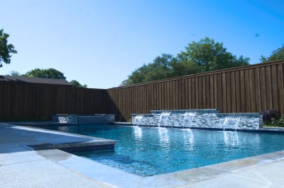 Complete view of the raised spa integration with multiple sheer descent water features showcasing Burlington Quartzite stonework in natural daylight.
