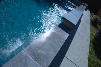 Burlington Quartzite Classico frames a stunning sheer descent water feature, creating a sophisticated cascade that enhances this Dallas luxury pool's serene ambiance.