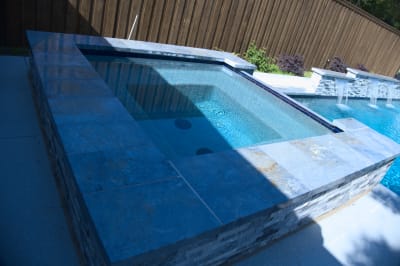 Burlington Quartzite Classico creates a refined spa perimeter where precise jets meet the raised beam structure. Natural lighting reveals the stone's subtle texture variations.