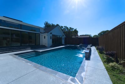 Sophisticated raised spa design featuring cascading sheer descents and Burlington quartzite classico coping creates dramatic water movement throughout this luxury outdoor living space.