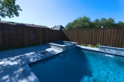 Burlington quartzite classico decking creates sophisticated outdoor living space with seamlessly integrated raised spa featuring multiple sheer descents.