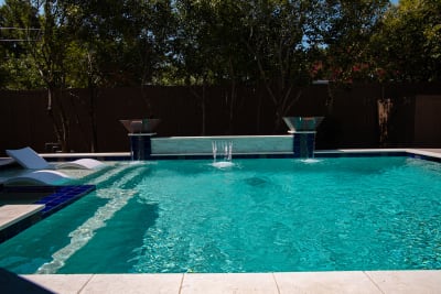 Close-detail view of art deco copper lotus waterline tile and NPT CRA-Bianco white raised beam wall veneer on a contemporary geometric pool in Dallas, TX.