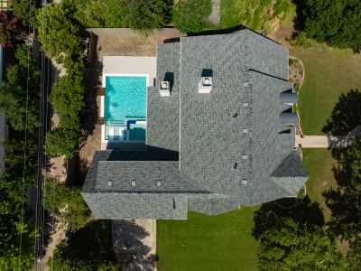 Aerial view of a contemporary geometric pool with art deco copper lotus waterline tile, two square copper water bowls, and Burlington Blanco travertine coping at a Dallas, TX residence.