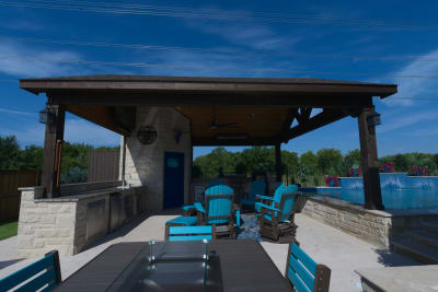 Architectural outdoor kitchen design seamlessly integrates with custom stone retaining walls, featuring premium granite countertops and natural stone masonry for elevated outdoor entertaining.