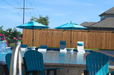 18-inch sheer descent creates dramatic water spillway accent with NPT Elysium peacock mosaic tile integration. Umbrella sleeve positioned within tanning ledge for seamless outdoor comfort.