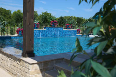 Multi-depth pool steps showcase premium Elysium Peacock 1x2 mosaic tile integration with natural stone coping in this Haslet wellness retreat.