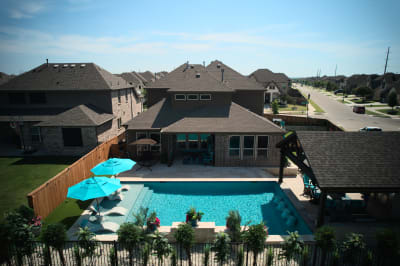 Exterior wide view showcasing the seamless integration of Belguard French pattern pavers with multi-depth pool steps and tanning ledge at the Olesky residence.