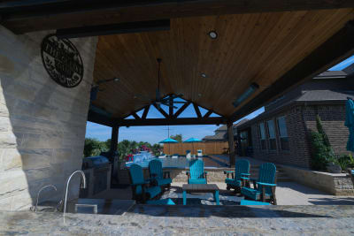 Architectural covered living space showcases exposed beam construction and ceiling details that complement the complete outdoor environment at the Olesky residence.