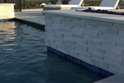 Close detail of 1"x1" glass tile on the raised geometric spa and marble back wall at a Tarrant County estate in Fort Worth, TX.