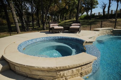 Establishing overview of a custom gathering pool with Buff Lueders coping, Regatta Blue pebble plaster, and three sheer descents crafted for a Fort Worth, Tarrant County, TX estate.