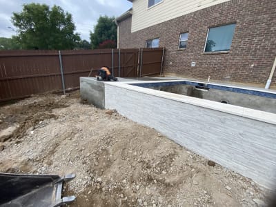 Early construction view of a geometric inground pool taking shape in Hurst, Tarrant County, TX, revealing the excavated form that will hold Caribbean Blue Peerless Pebble and three 18-inch sheer descents.