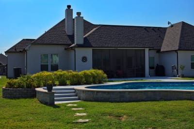 Wide view of a naturalistic freeform pool with Grey Leuders stone coping, spray deck in Perla, and oversized circular spa at a private Azle, Parker County, TX residence.
