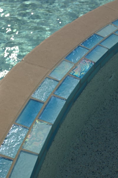 Close detail of a 42-inch Grey Leuders stone veneer fire pit anchoring the naturalistic outdoor living space at a freeform pool estate in Azle, TX.