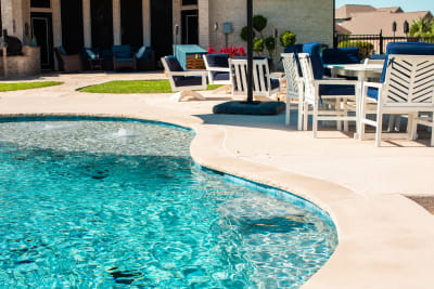 Curved freeform pool edge with outdoor lounge furniture and navy cushions showing the southwestern pool design at the Sharp residence in Granbury, TX