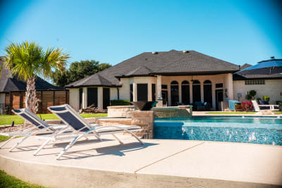 Deck-side view with lounge chairs and palm tree alongside the freeform pool and elevated spa at the Sharp residence in Granbury, TX