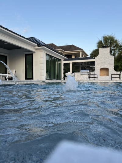 Luxury outdoor pool with water feature, spa, pergola, and raised beam at the Sheldon Residence in Miramar Beach, FL.