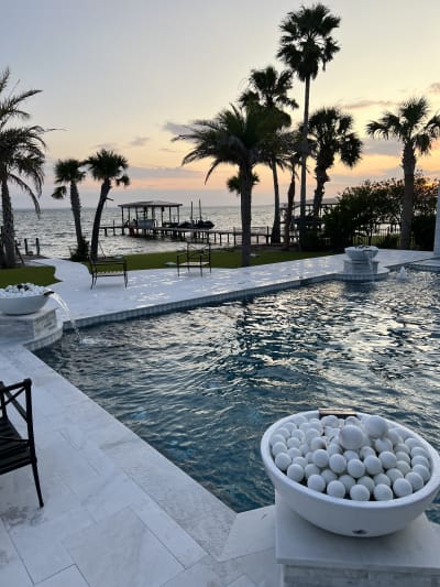 Luxury outdoor pool and spa with raised beam, sheer descent, pergola, and tanning ledge at the Sheldon Residence in Miramar Beach, FL.