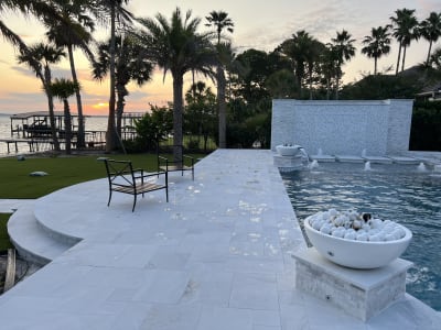 Luxury pool with fountains, spa, fire feature, and waterfront sunset views at the Sheldon Residence in Miramar Beach, FL.