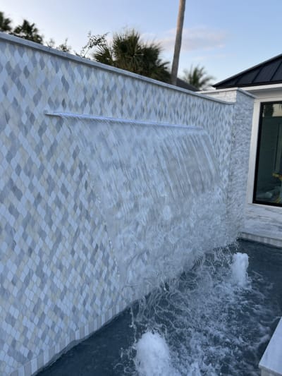 Travertine spa and water feature at the Sheldon Residence, a luxury outdoor pool installation in Miramar Beach, FL.