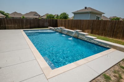 Establishing overview of a contemporary geometric pool with Arctic White pebble plaster finish, Noble Platinum Ice coping, and March Wind spray deck in North Richland Hills, TX.