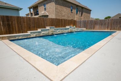Aerial view of a 34-by-15-foot geometric pool with Arctic White pebble plaster finish, NPT Parallax PLL Blue waterline tile, and Noble Platinum Ice bull nose coping in North Richland Hills, TX.