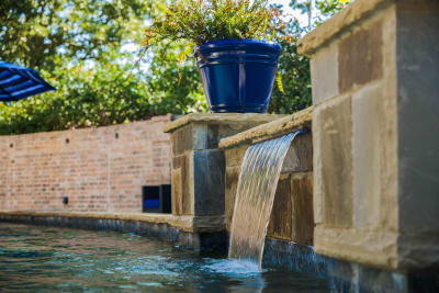 Close-detail view of a cascading waterfall feature flowing into a custom pool, showcasing natural stone hardscape integration at a Tarrant County outdoor living space in Arlington, TX.