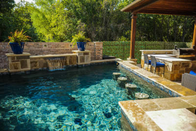Multi-zone outdoor living space featuring an inground spa and paver patio deck crafted for family living at a Tarrant County estate in Arlington, TX.