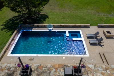 Aerial view of a 34' x 18' rectangular gunite pool with dual bubblers and spillover custom spa in Red Oak, Ellis County, TX.