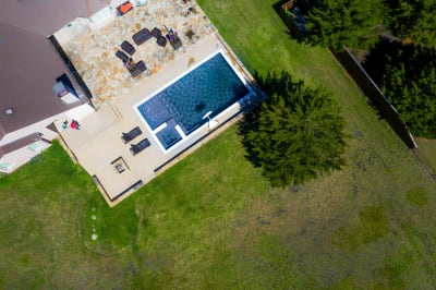 Establishing overhead view of a 34x18 rectangular gunite pool with spillover custom spa and dual bubblers in a Red Oak, TX outdoor living space.