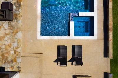 Aerial view of a 34' x 18' rectangular pool and 7' x 7' gunite custom spa with stone coping and tile finishes in Red Oak, Ellis County, TX.