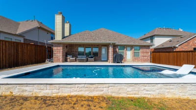 Close material detail of Burlington Blanco coping meeting Noble NPOS 634 Circe waterline tile at the geometric pool edge in Roanoke, TX.