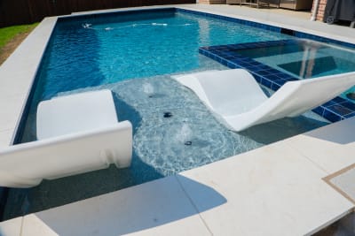 Close detail of a 16-foot flat spillover with Noble NPOS 634 Circe waterline tile and Burlington Blanco coping at the Vannoy Residence in Roanoke, TX.