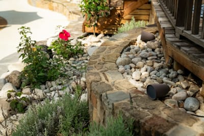 Wide view of a naturalistic freeform pool with Oklahoma stone coping and wood-accented fireplace structure in an Arlington, Tarrant County, TX outdoor living space.