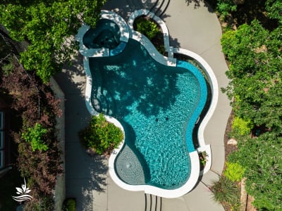 Raised spa with Burlington Carra White travertine ledgestone veneer and cedar structure framing a spillway feature in a Grapevine, TX outdoor living space.