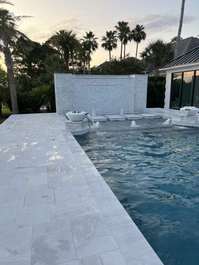 Luxury backyard pool with travertine patio, pergola, spa, and outdoor kitchen designed for a Miramar Beach, FL residence.