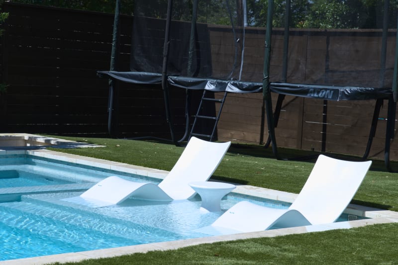 The tanning ledge showcases precision coping installation and coordinated tile borders, creating seamless transitions in this Champion Residence project.