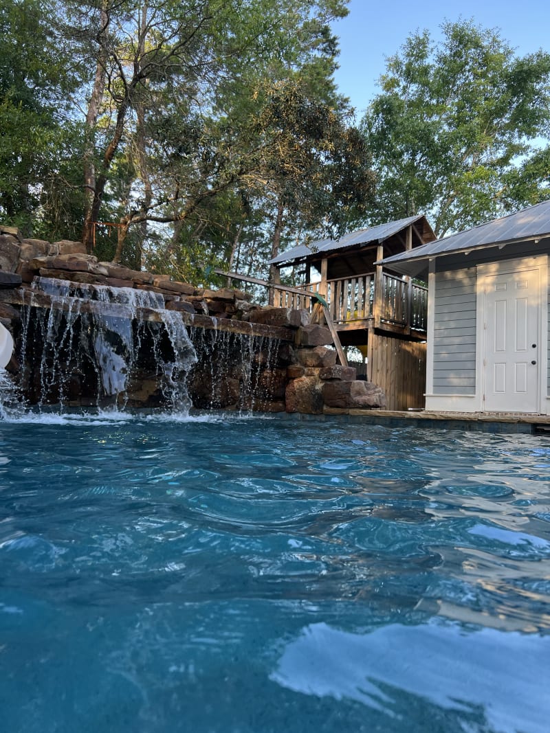 Outdoor pool with waterfall feature and poolside cabana at the Colon Residence in Santa Rosa Beach, FL.