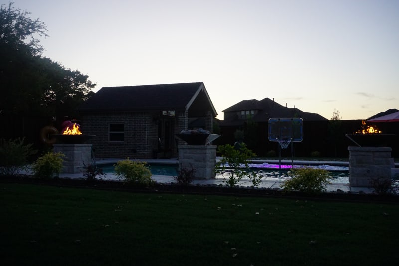 Wide view of a 9-foot linear natural gas fire pit along the multi-level pool deck, with Leudar Buff coping and Arctic White Peerless Pebble water at a Tarrant County estate in Arlington, TX.