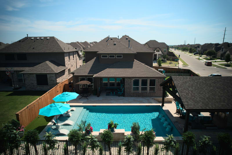 Exterior wide view showcasing the seamless integration of Belguard French pattern pavers with multi-depth pool steps and tanning ledge at the Olesky residence.