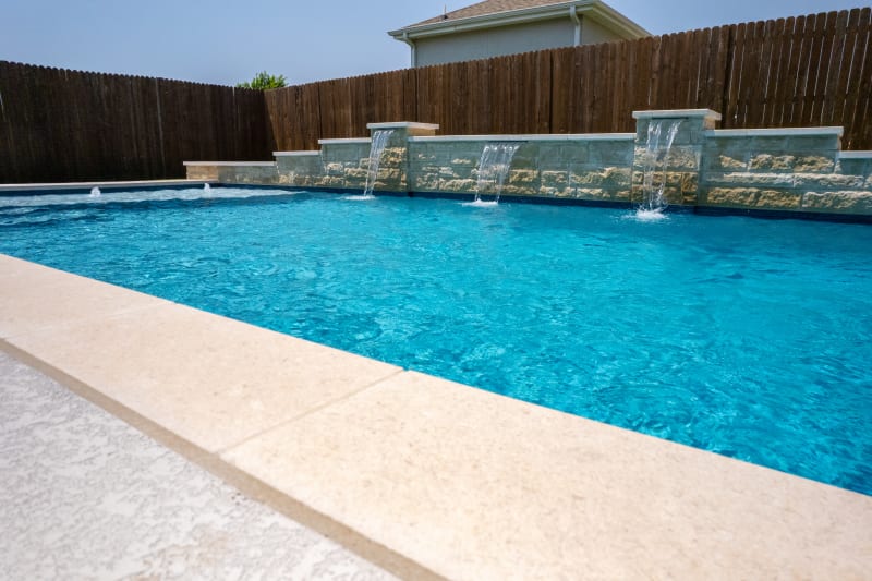 Establishing overview of a contemporary geometric pool with Arctic White pebble plaster finish, Noble Platinum Ice coping, and March Wind spray deck in North Richland Hills, TX.