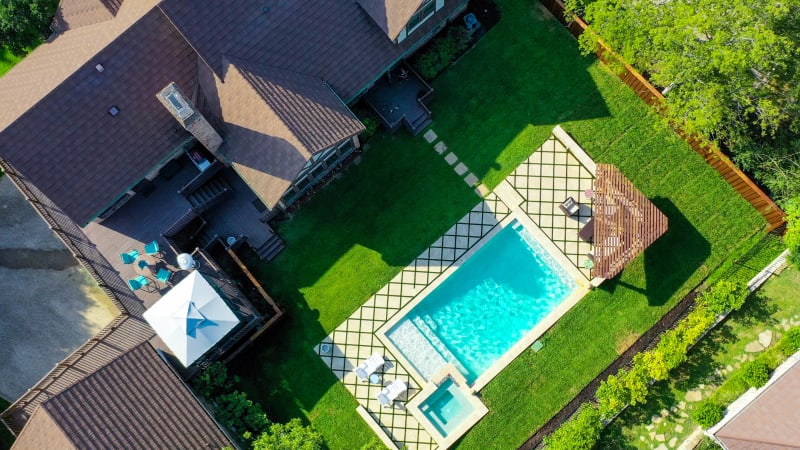 Integrated love seats built into a custom pool with marble quartz plaster finish, travertine coping, and stone veneer spa surround in Irving, TX.