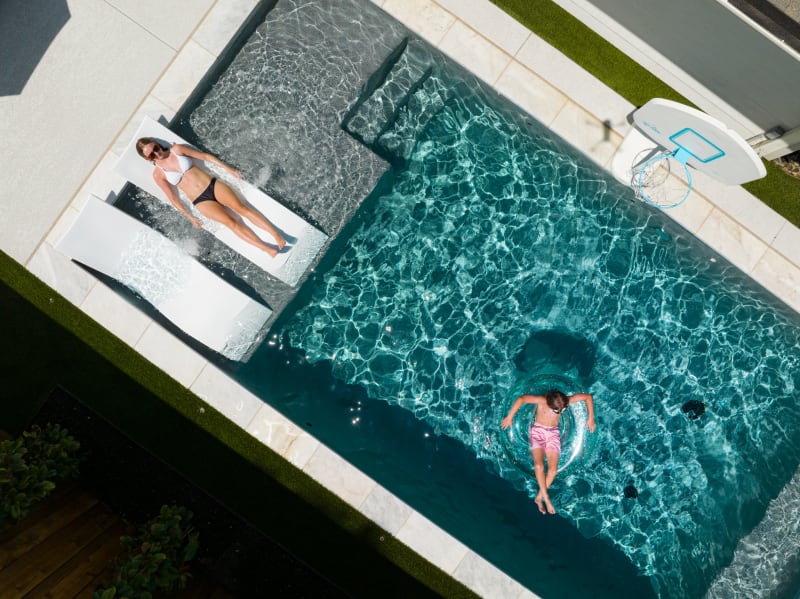 Aerial view of a geometric pool and spa retreat with tanning ledge and travertine decking in University Park, TX by Selah Pools