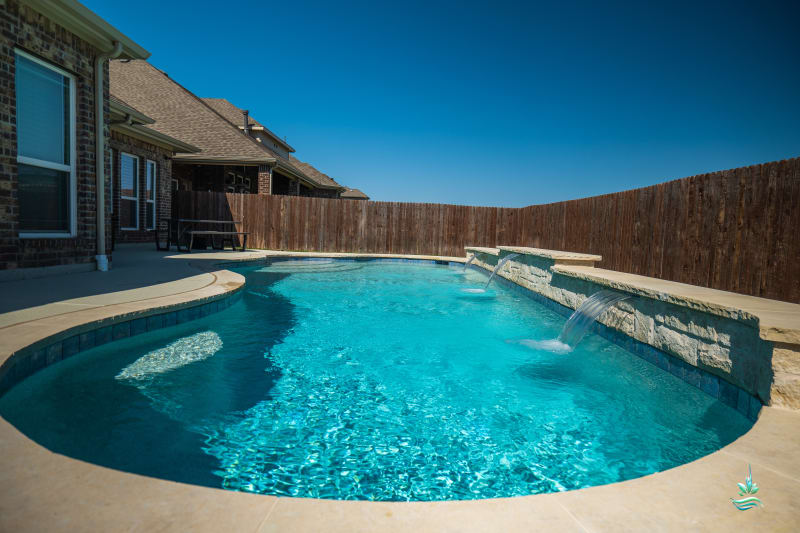 Aerial view of a raised spillover spa with Buff Lueders stone veneer and Aquabella Greek Isles GR662 tile alongside an oversized tanning ledge in Fort Worth, TX.