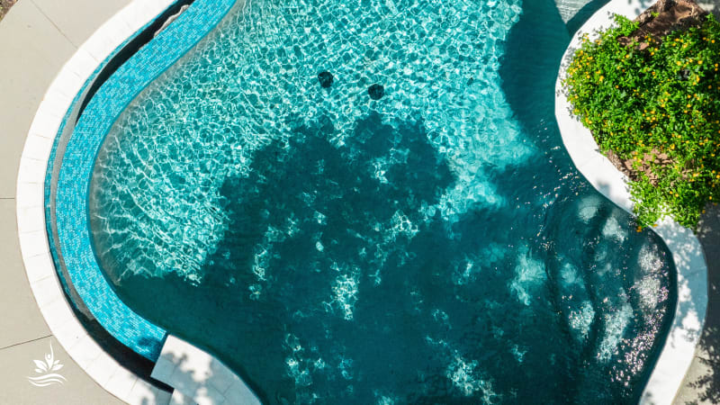 Aerial overview of a renovated infinity-edge pool with raised spa, travertine ledgestone, and cedar structure in Grapevine, TX by Selah Pools
