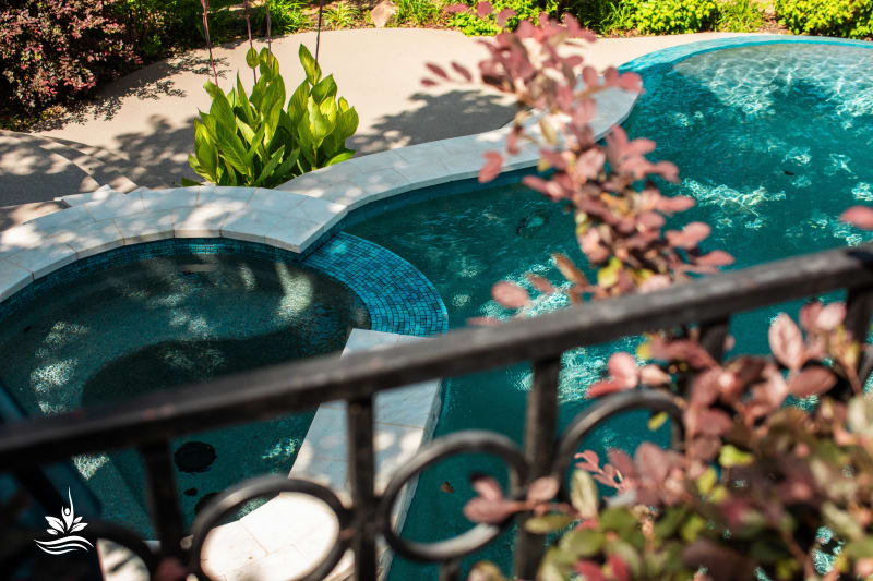 Raised spa with travertine ledgestone veneer and a 19-foot forward infinity edge spillway cascading into the catch basin at a Grapevine, TX estate.